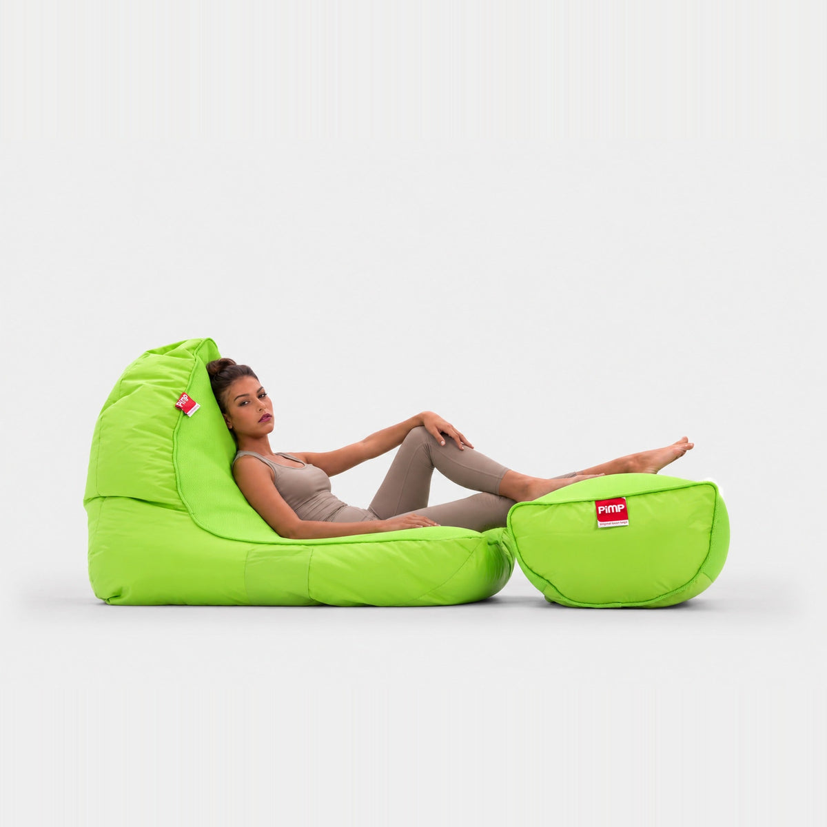 Coolio Wild Lime green beanbag sofa and matching footrest with a woman reclining